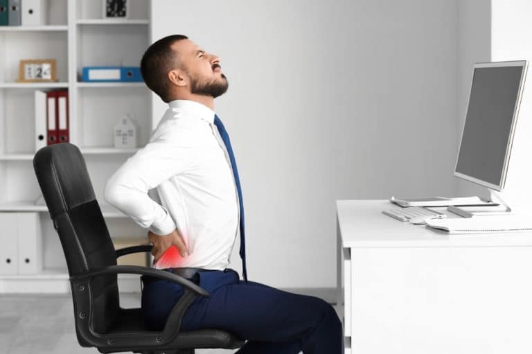 A man struggles with back pain while at work